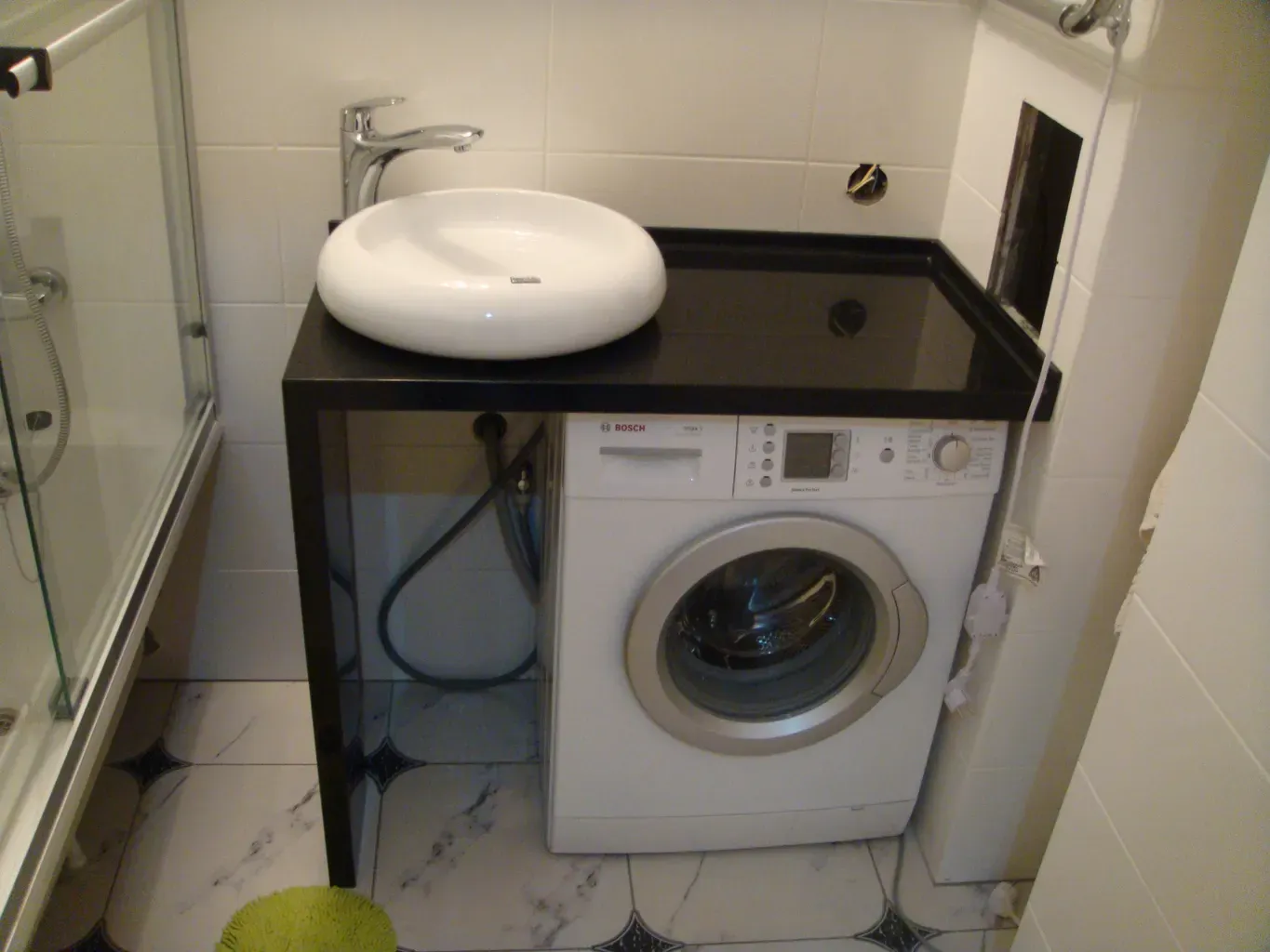 Черная акриловая поверхность в сочетании с белоснежной керамикой. Г-образная форма позволяет объединить зону умывальника и прачечную в один стильный объем.